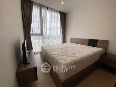Modern bedroom with large window and stylish furniture in high-rise apartment.