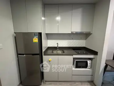 Modern compact kitchen with sleek cabinetry and built-in appliances in a stylish apartment.