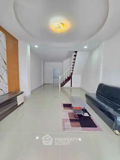 Spacious modern living room with sleek design and elegant staircase, perfect for contemporary living.