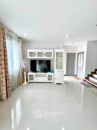 Spacious living room with modern entertainment center and elegant curtains