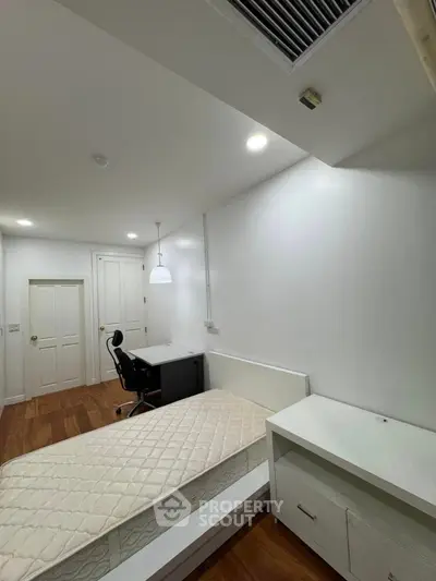 Spacious bedroom with study desk and modern lighting, ideal for comfort and productivity.