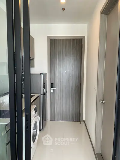 Modern apartment entrance with sleek kitchen appliances and washing machine