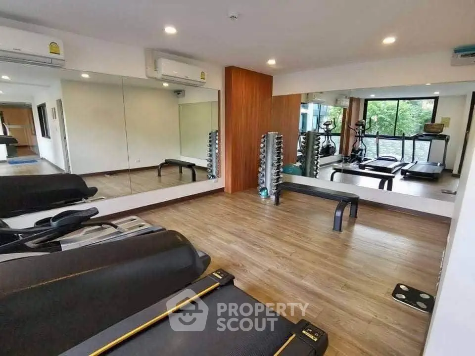 Modern gym with treadmills and mirrored walls in a residential building.