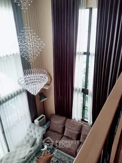 Luxurious high-ceiling living room with elegant chandelier and floor-to-ceiling windows.