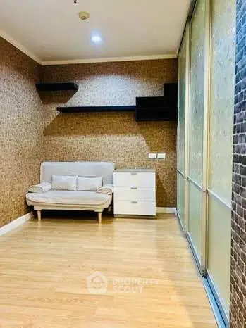 Spacious room with modern decor and wooden flooring, featuring a cozy sofa and sleek storage unit.