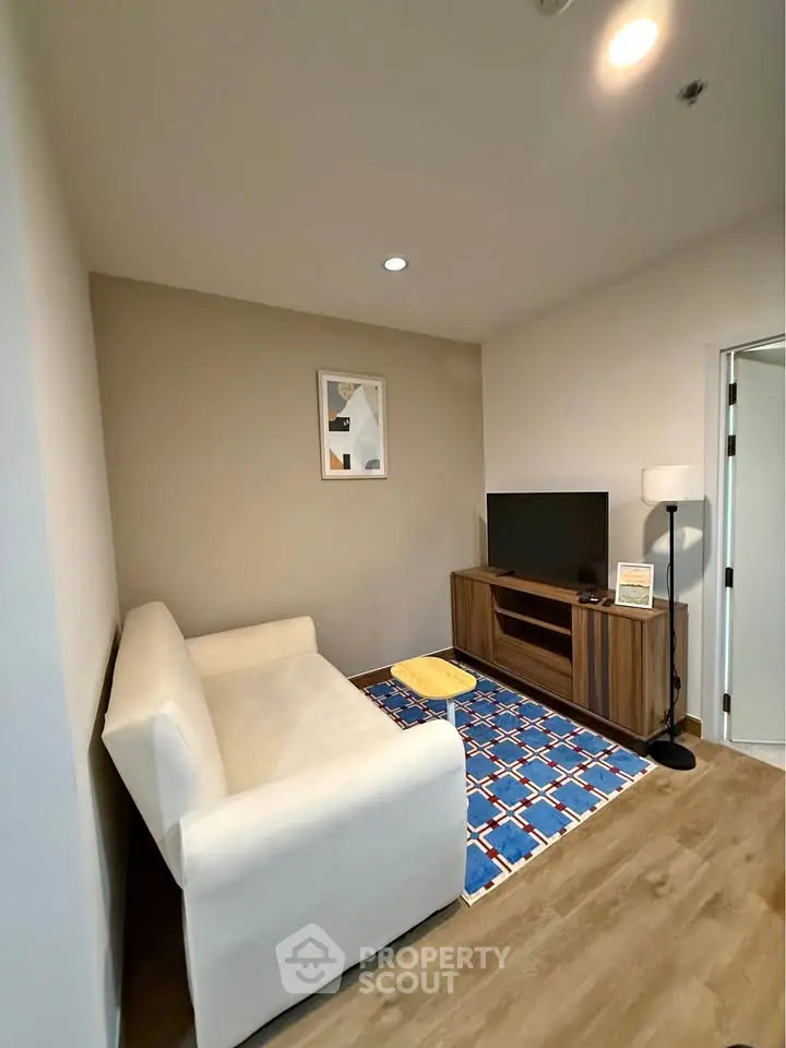 Cozy living room with modern decor, featuring a white sofa, flat-screen TV, and stylish wooden cabinet.