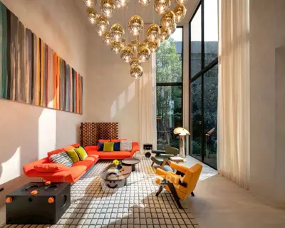 Stunning modern living room with high ceilings, vibrant furniture, and floor-to-ceiling windows.