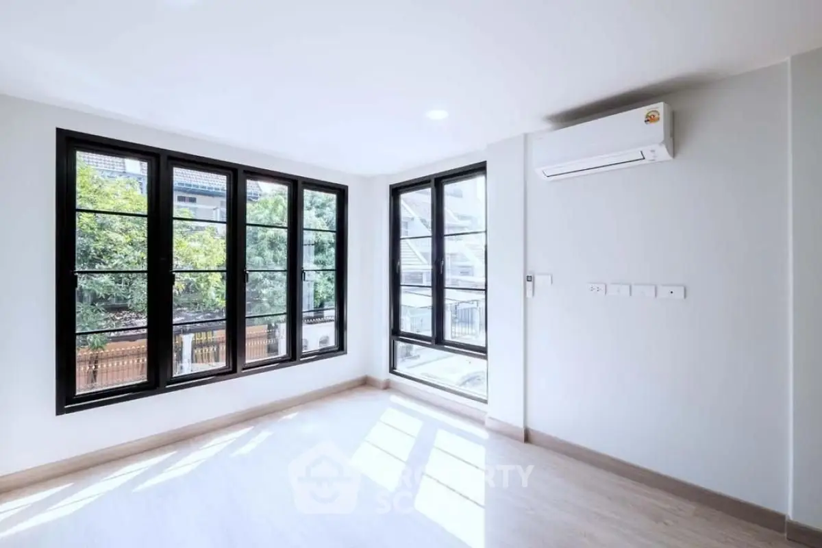 Bright empty room with large windows and air conditioning, perfect for modern living.