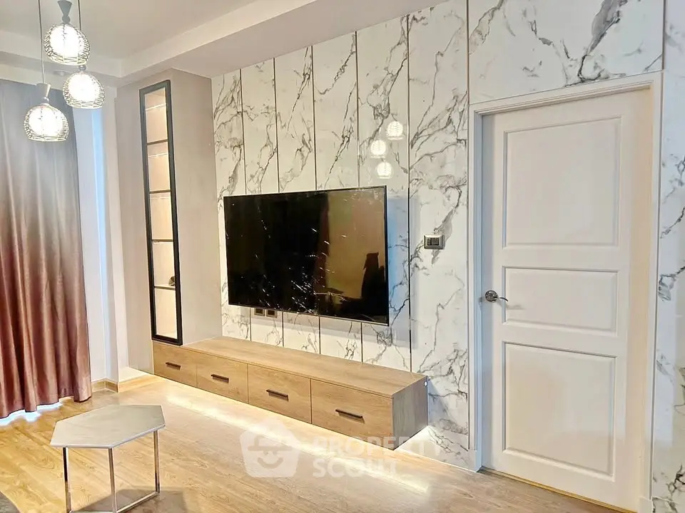 Modern living room with marble accent wall and mounted TV, featuring elegant lighting and wooden flooring.