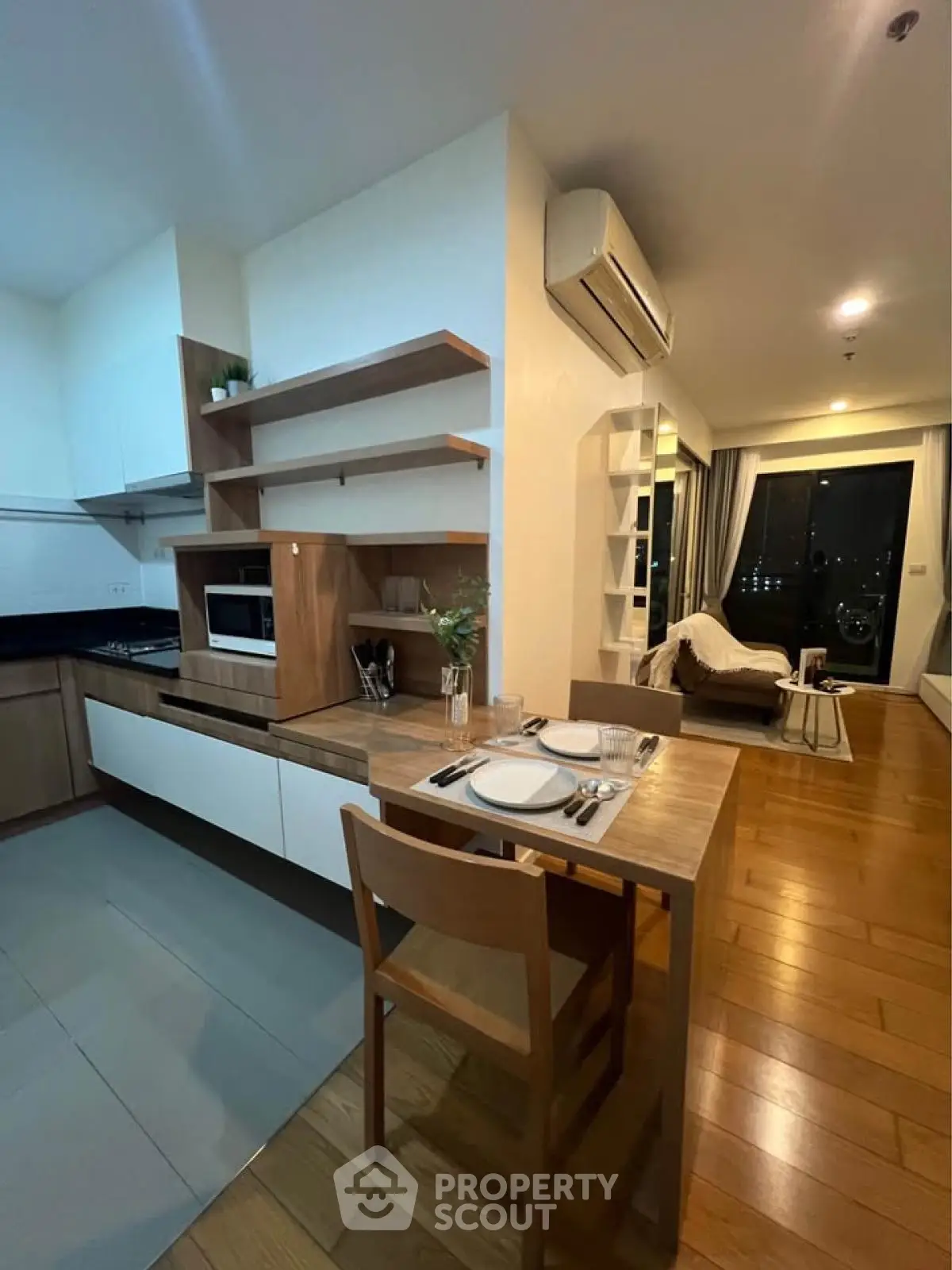 Modern open-layout kitchen and living room with stylish wooden flooring and sleek appliances.