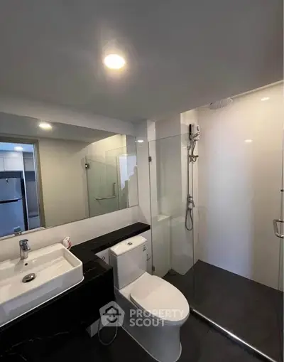 Modern bathroom with sleek fixtures and glass shower enclosure in a contemporary apartment.