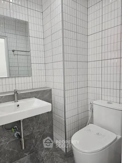 Modern bathroom with sleek white tiles and contemporary fixtures.