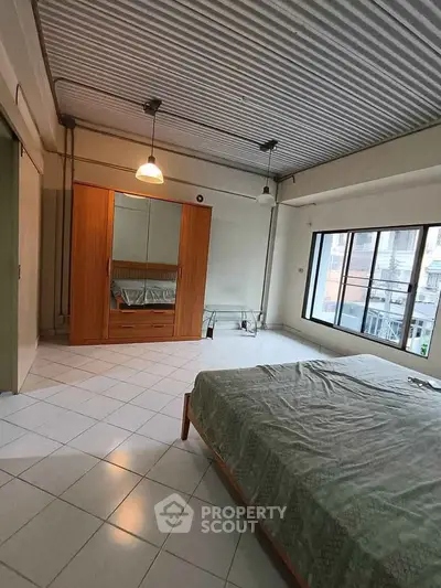 Spacious bedroom with large window and modern wardrobe in urban apartment