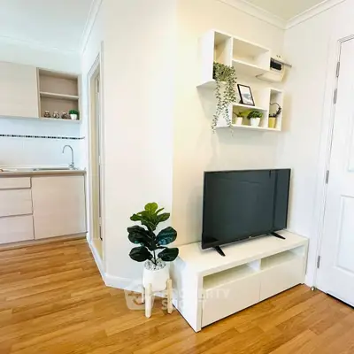 Cozy living room with modern TV setup and open kitchen layout.