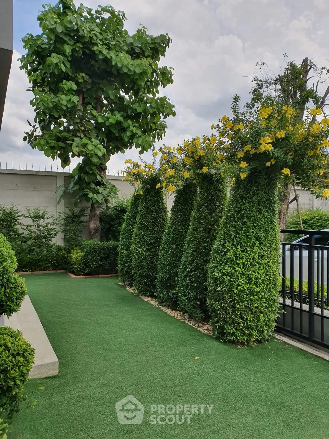 Lush green garden with manicured hedges and trees in a serene residential setting.
