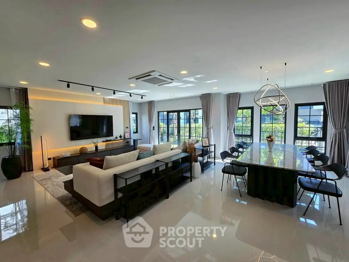 Spacious modern living room with elegant dining area and large windows offering natural light.