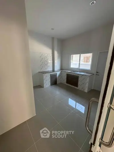 Modern kitchen with sleek tile flooring and ample natural light from large windows.
