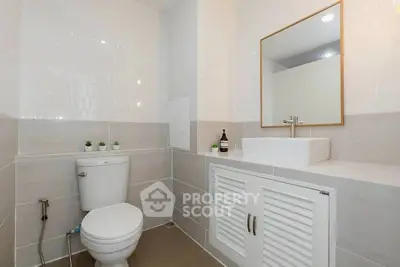 Modern bathroom with sleek fixtures and neutral tiles, featuring a stylish vanity and mirror.