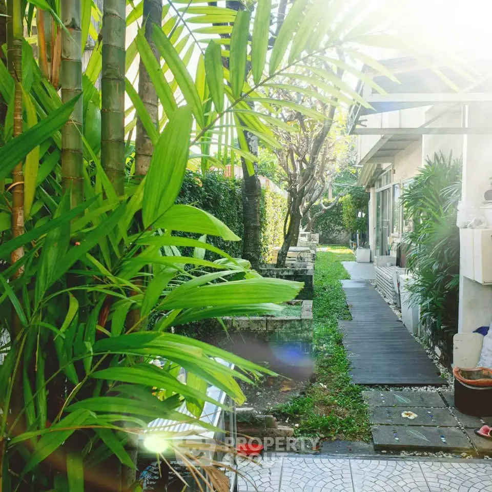 Lush garden pathway leading to a modern home entrance, surrounded by vibrant greenery and natural light.