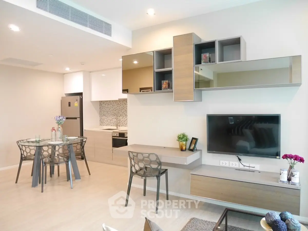 Modern open-plan living room with stylish kitchen and dining area, featuring sleek furniture and contemporary decor.