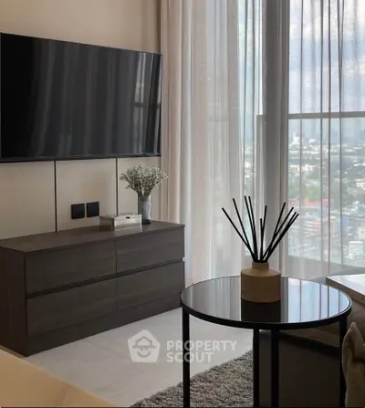 Modern living room with large TV and city view, featuring sleek furniture and elegant decor.