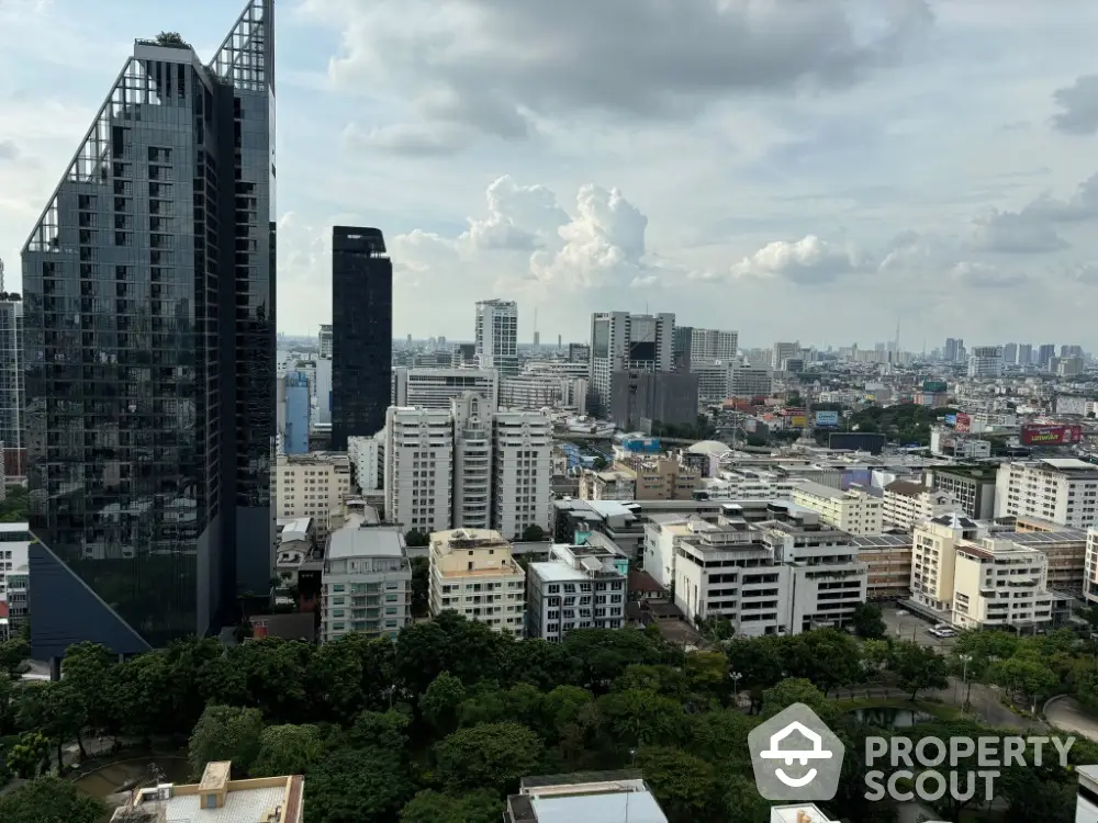 Stunning cityscape view from high-rise apartment with lush greenery and modern architecture.