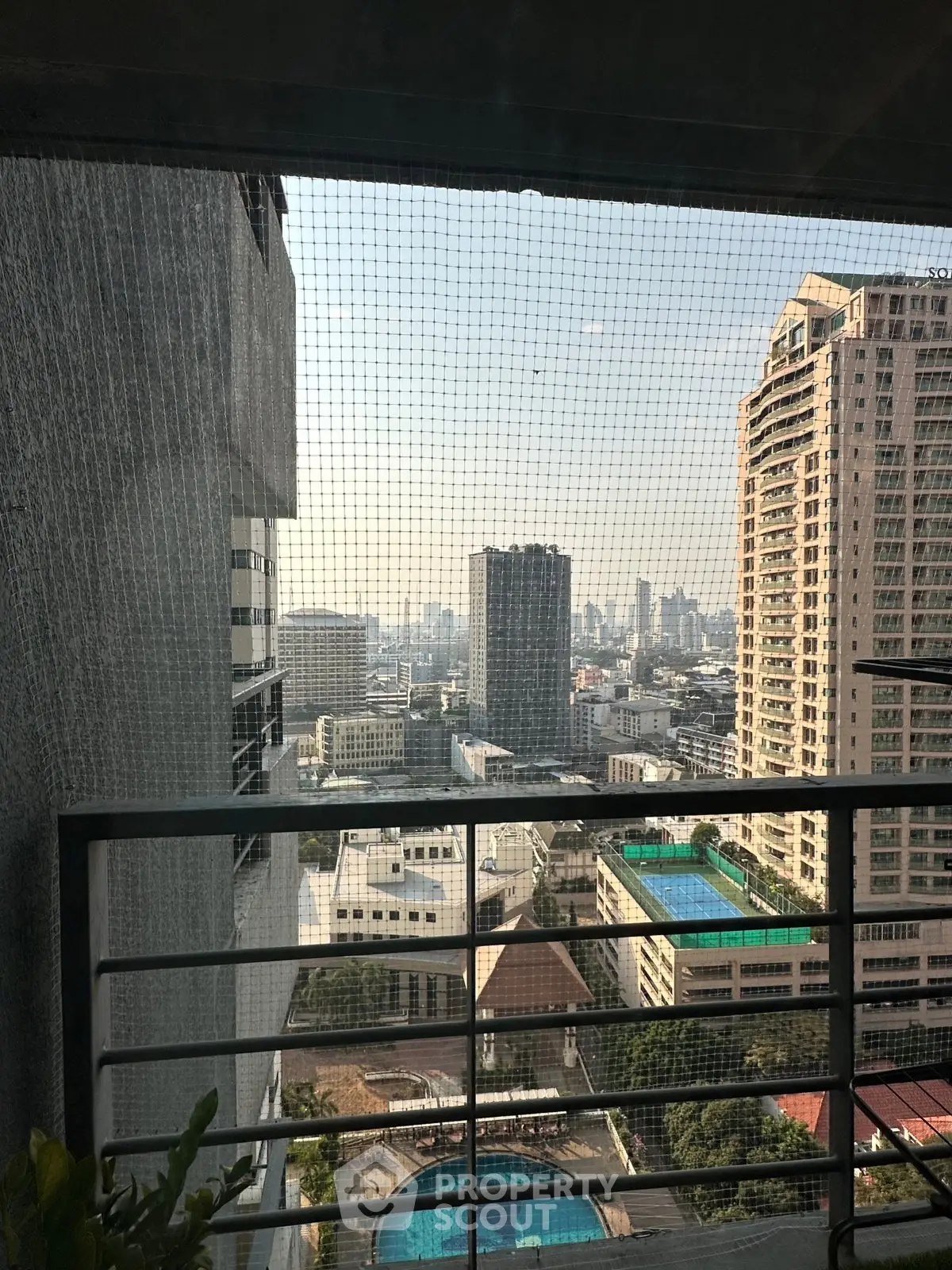 Stunning cityscape view from a high-rise balcony overlooking urban skyline and pool area.