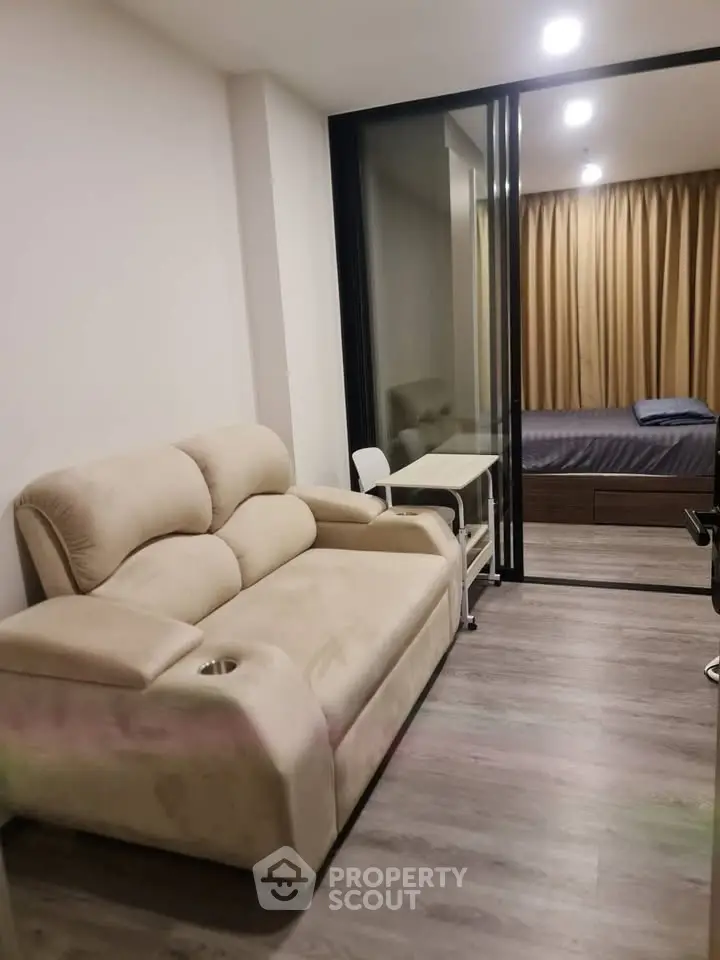 Modern apartment with cozy living room and bedroom separated by glass partition.