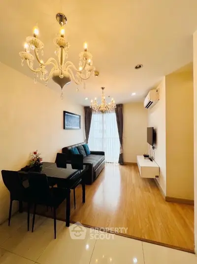 Elegant living room with chandelier and modern decor, featuring a cozy seating area and wall-mounted TV.