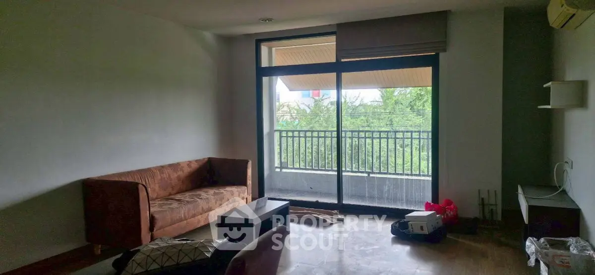 Spacious living room with balcony view, featuring modern sofa and natural light.
