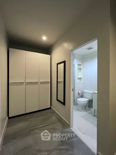 Modern hallway with sleek closet leading to a contemporary bathroom