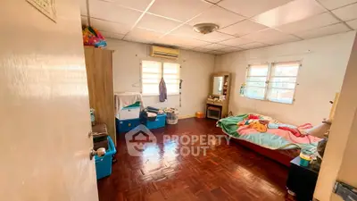 Spacious bedroom with wooden flooring and ample natural light, featuring a cozy bed and storage solutions.