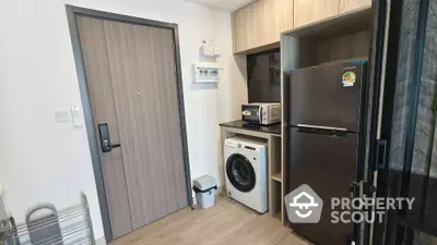 Modern kitchen with washing machine, fridge, and microwave in compact layout.