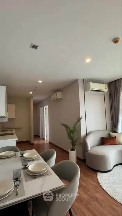Modern living room with elegant dining area and cozy seating, featuring air conditioning and stylish decor.