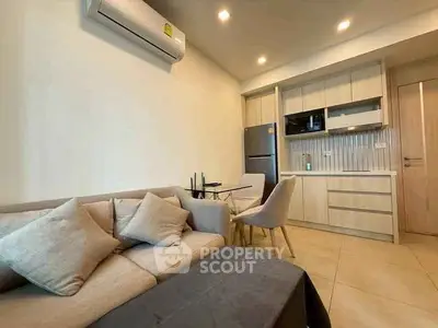 Modern open-layout kitchen and cozy living area with neutral tones and sleek design.