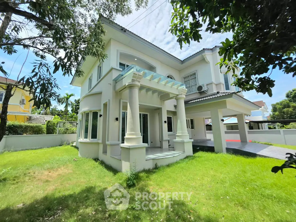 Stunning two-story house with lush garden and elegant columns in a serene neighborhood.