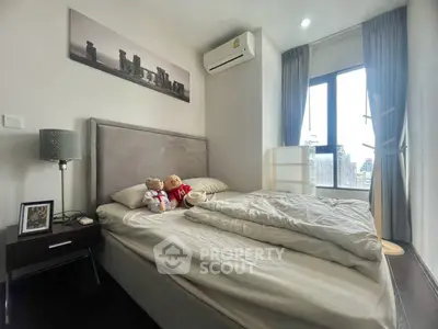 Cozy bedroom with modern decor, featuring a plush bed, stylish lamp, and large window with city view.