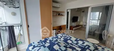 Modern bedroom with balcony access and view into living room, featuring stylish decor and ample natural light.