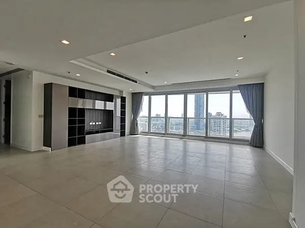Spacious modern living room with large windows offering stunning city views.