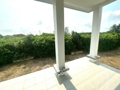 Spacious outdoor patio with lush greenery and modern design, perfect for relaxation and entertaining.