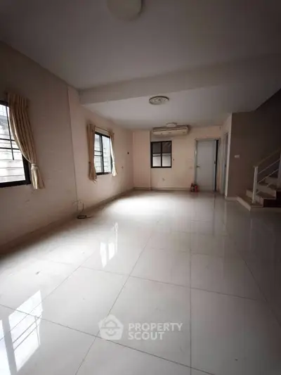 Spacious empty living room with large windows and tiled flooring, perfect for customization.