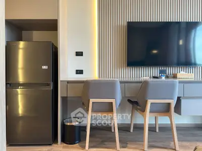 Modern kitchen with sleek fridge and stylish seating area, perfect for contemporary living.