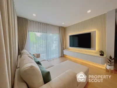 Modern living room with large TV and cozy sofa, featuring elegant curtains and wooden flooring.