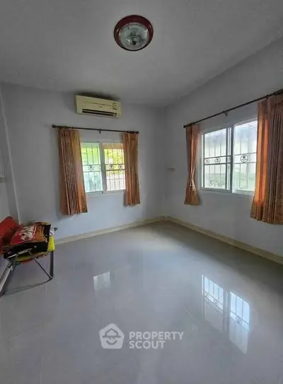 Spacious empty room with large windows and air conditioning, perfect for customization.