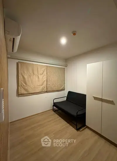 Cozy minimalist room with wooden flooring and modern furnishings, perfect for a compact living space.