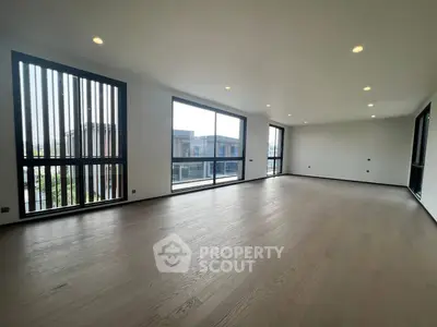 Spacious modern living room with large windows and wooden flooring in a luxury apartment.