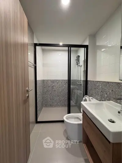 Modern bathroom with sleek design, featuring a glass shower enclosure and stylish fixtures.
