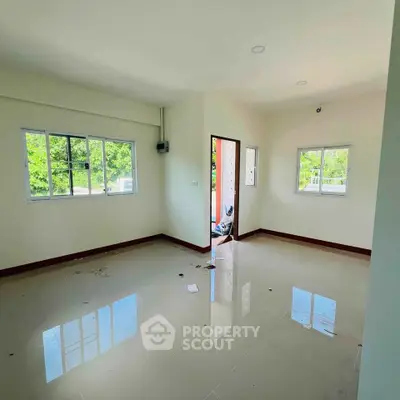 Spacious unfurnished living room with large windows and glossy tiled floor, offering abundant natural light.