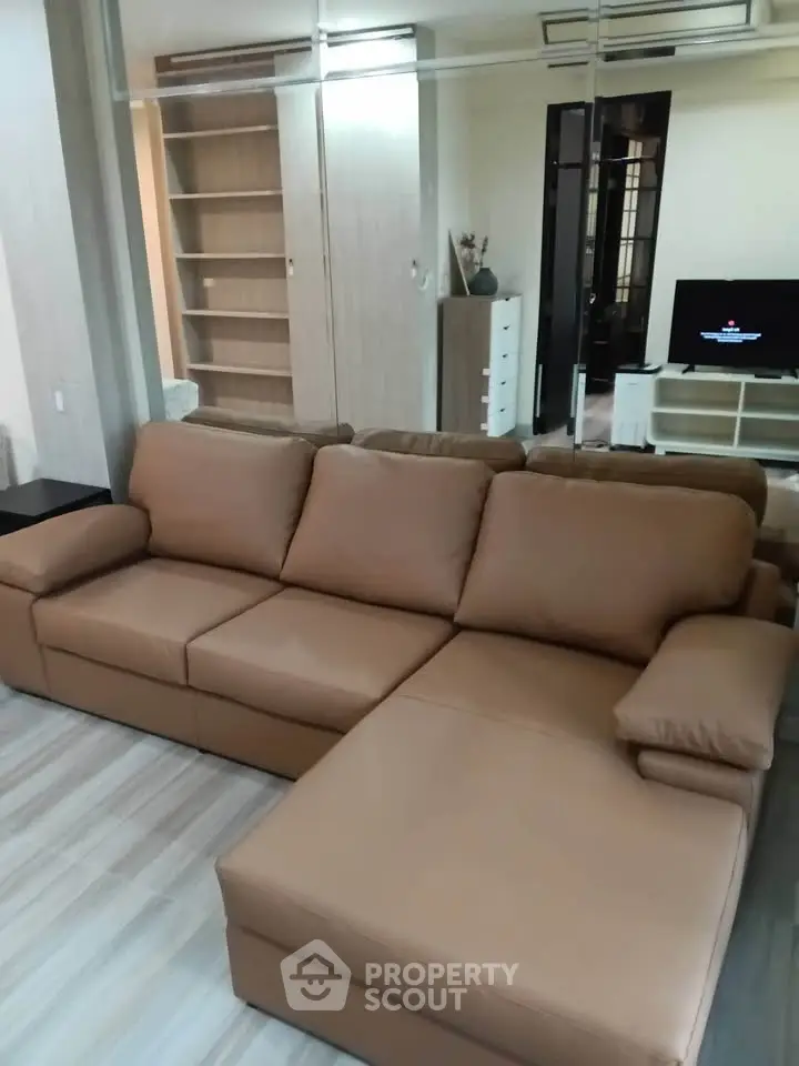 Spacious living room with modern leather sofa and sleek wooden flooring