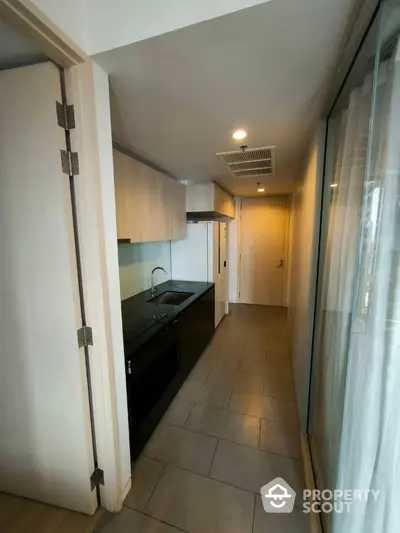 Modern compact kitchen with sleek cabinetry and built-in appliances in a narrow corridor layout.